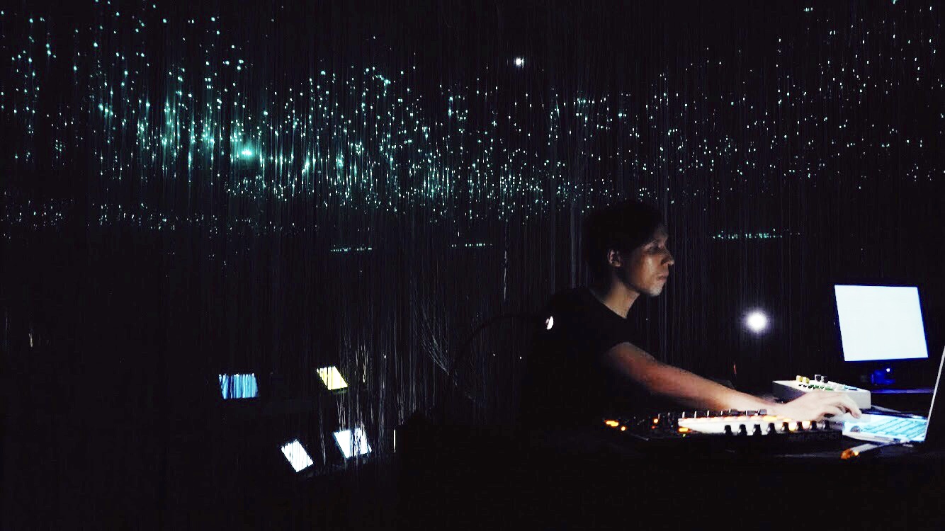 Po-Hao Chi playing a MIDI controller and laptop under hanging fiber-optic lights during Duplex Transmission, Taipei 2019