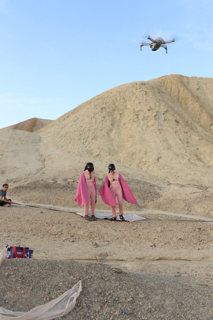 Drone flying above two performers before the pale badlands of Death Valley National Park