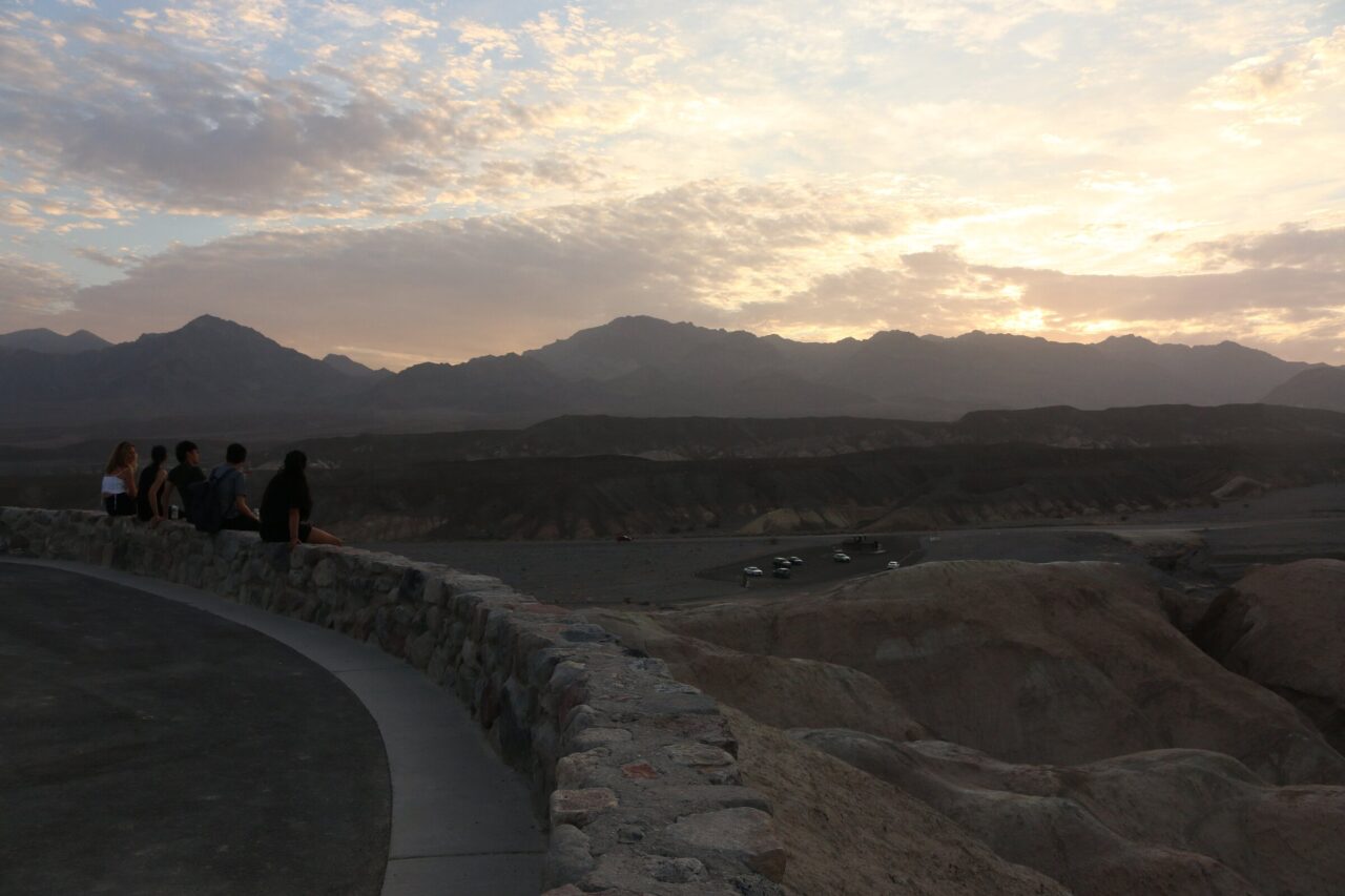 Field team at a stone overlook above Death Valley badlands at sunset
